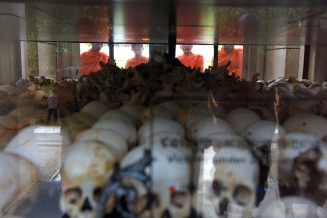 Cambodian monks pray in front of skulls of those killed by the Khmer Rouge regime at the C