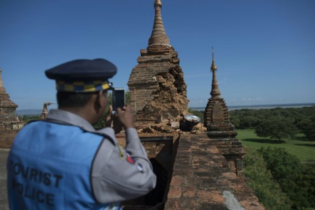 A police officer records the damage at Htilominlo Temple on August 25, 2016, after a 6.8 m