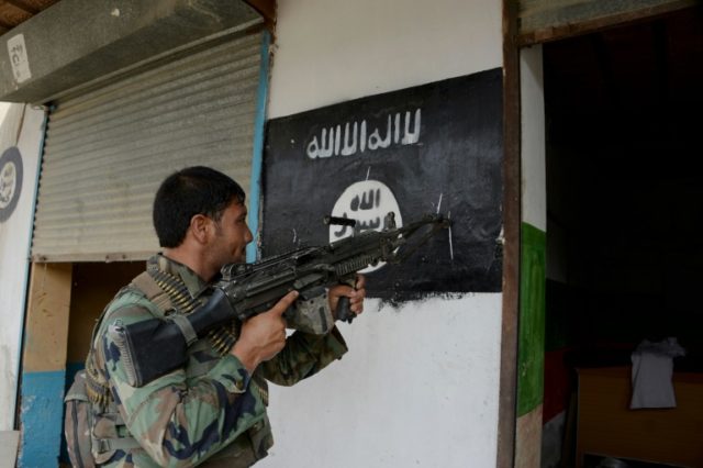 An Afghan soldier points his gun at an Islamic State group banner as he patrols during ong