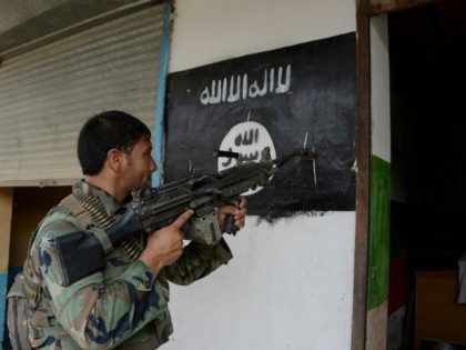 An Afghan soldier points his gun at an Islamic State group banner as he patrols during ong