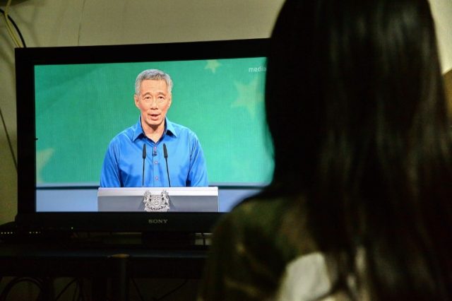 A Singaporean resident watches a live televised speech by Prime Minister Lee Hsien Loong a