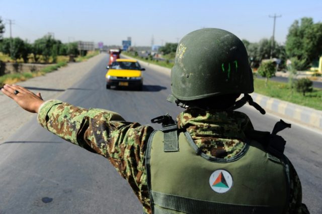 An Afghan National Army (ANA) soldier stops a car at a security checkpoint in Herat on Jun