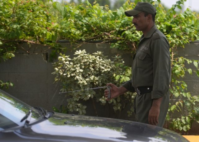 A Pakistani private security guard uses an explosives detector to search a vehicle at a ma