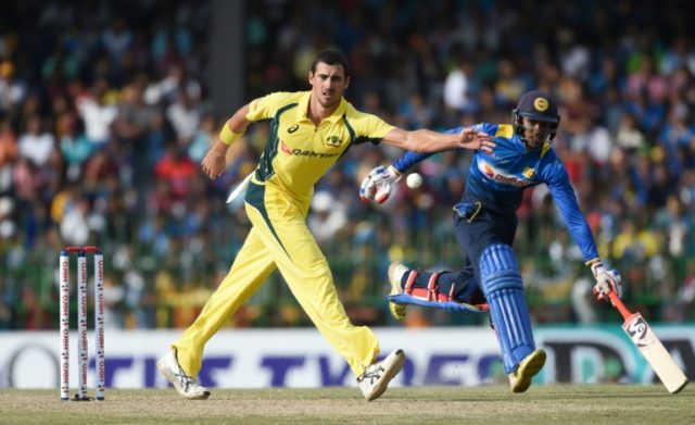 Australia's Mitchell Starc stops a ball as Sri Lankan batsman Dhananjaya de Silva (right)