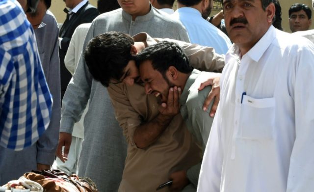 Pakistani local journalists react over the body of a news cameraman after a bomb explosion