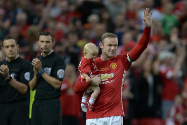 Manchester United's striker Wayne Rooney (R) waves to the crowd, holding his son Kit. befo