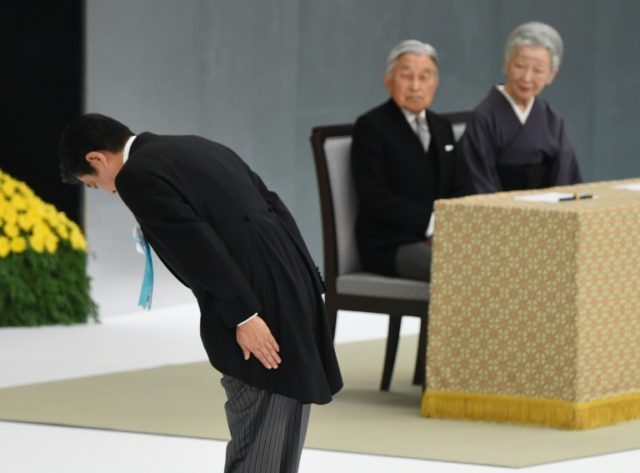 Japanese Prime Minister Shinzo Abe (L) bows to an altar beside Emperor Akihito and Empress