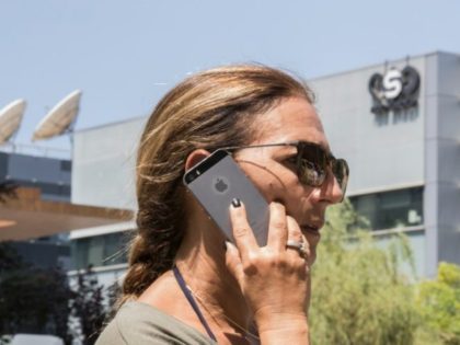 An Israeli woman uses her iPhone in front of the building housing the Israeli NSO group, on August 28, 2016, in Herzliya, near Tel Aviv