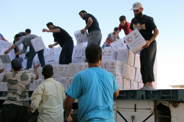 This photo taken on July 26, 2016 shows Syrians unload boxes after a 48-truck convoy from