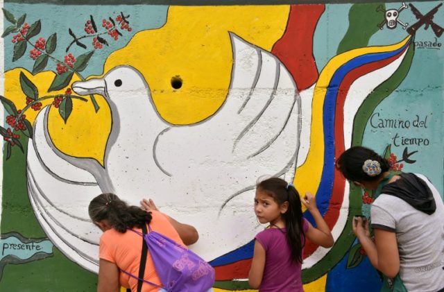 Locals paint a mural on the road leading to Planadas, Tolima department, about the peace d