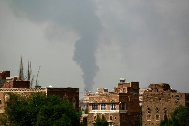 Smoke billows behind buildings in the Yemeni caiptal following a reported airstrike carrie