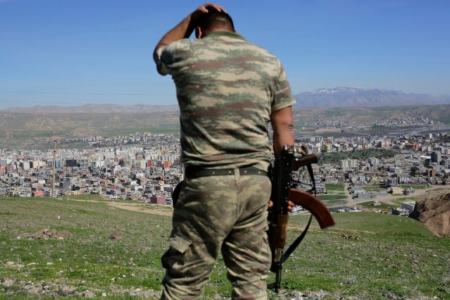 A Turkish soldier gestures while standing on a hill overlooking Cizre in southeastern Turk