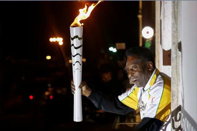 Former football player Pele holds the Olympic flame at the Pele Museum in Santos, Sao Paul