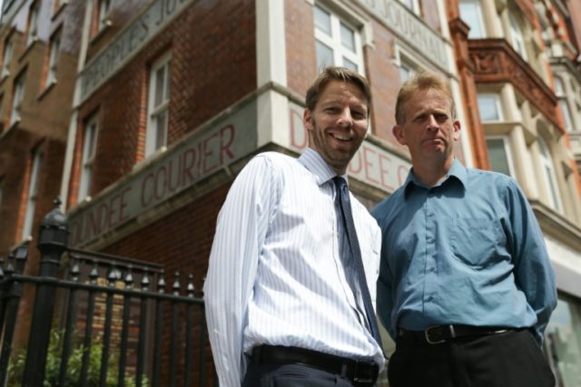 Reporters Darryl Smith (L) and Gavin Sherriff pose for a picture outside the building on F
