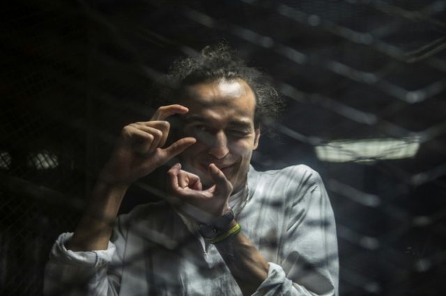 Egyptian photographer Mahmoud Abdel Shakour, known as Shawkan, gestures from inside a soun