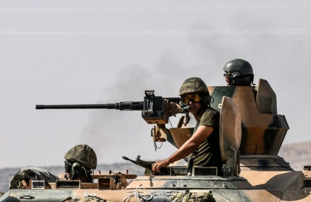 Turkish soldiers drive a tank towards the Syrian border from the Turkish city of Karkamis