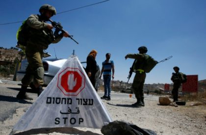 Israeli soldiers control Palestinians at an entrance of the al-Fawwar refugee camp, south