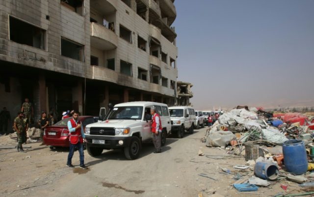 Red Crescent ambulances and Syrian army soldiers gather in the government-controlled part