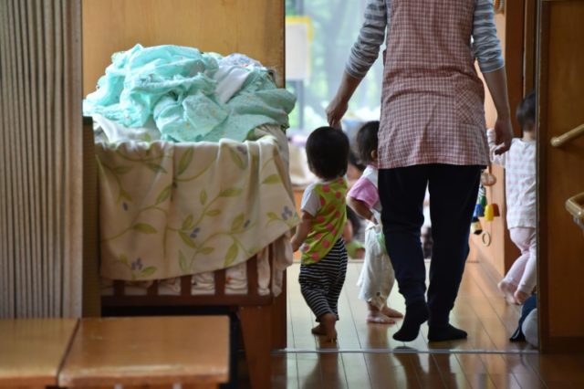 An employee of an official nursery school takes care of young children in Yokohama