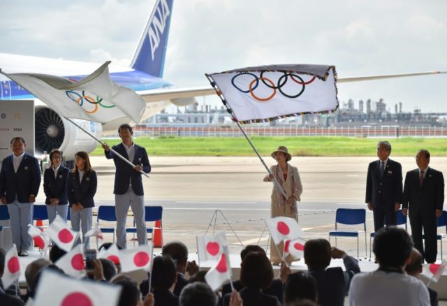 Tokyo governor Yuriko Koike (C) waves the Olympic flag as she is welcomed by well-wishers