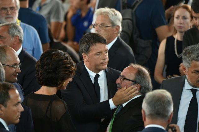 Italy's Prime Minister Matteo Renzi (C) embraces Arquata's mayor Leandro Petrucci during a