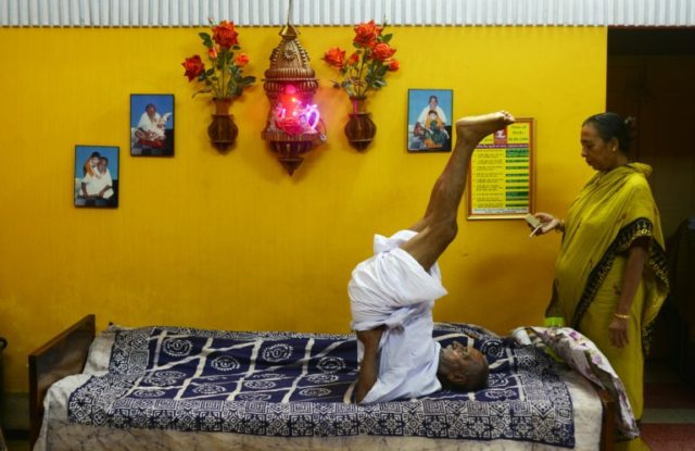 Indian monk Swami Sivananda (C), who claims to be 120 years old, is watched by one of his