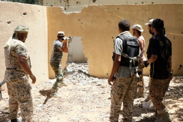 Forces loyal to Libya's UN-backed Government of National Accord break up a wall as they fi