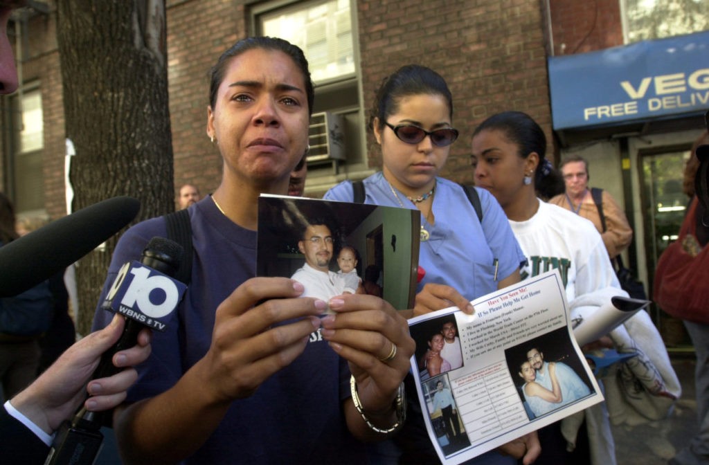 In this September 13, 2001 photograph, a woman poses with a picture of a missing loved one who was last seen at the World Trade Center when it was attacked on September 11, 2001.(AP Photo/Kathy Willens)