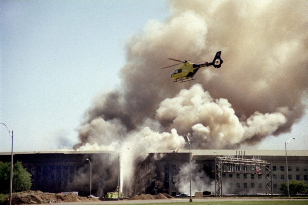 A helicopter flies over the Pentagon in Washington, Tuesday, Sept. 11, 2001 as smoke billows over the building. The Pentagon took a direct, devastating hit from an aircraft and the enduring symbols of American power were evacuated as an apparent terrorist attack quickly spread fear and chaos in the nation's capital. (AP Photo/Heesoon Yim)