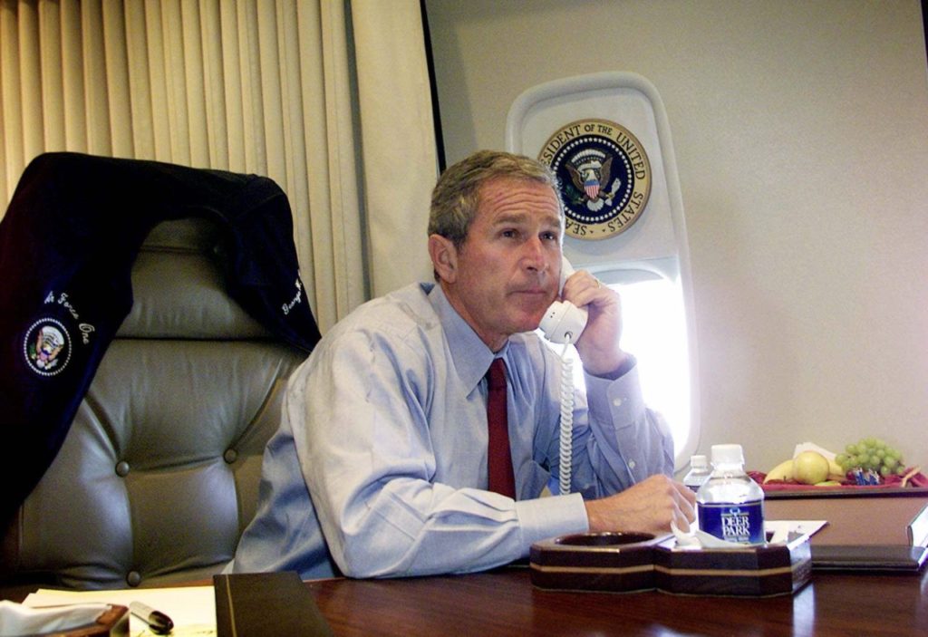 President Bush watches television as he talks on the phone with New York Mayor Rudy Giuliani and Gov. George Pataki aboard Air Force One during a flight following a statement about the terrorist attack on the World Trade Center in New York City, Tuesday, Sept. 11, 2001. (AP Photo/Doug Mills)