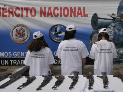 Four alleged members of the Revolutionary Armed Forces of Colombia (FARC) stand by weapons as they are presented to the press at a military base in Medellin, Colombia, Saturday Aug. 28, 2010.