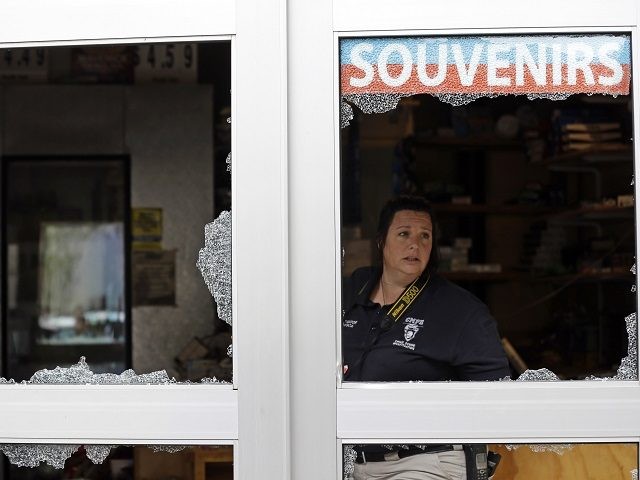A crime scene photographer looks out a storefront damaged overnight by protesters followin