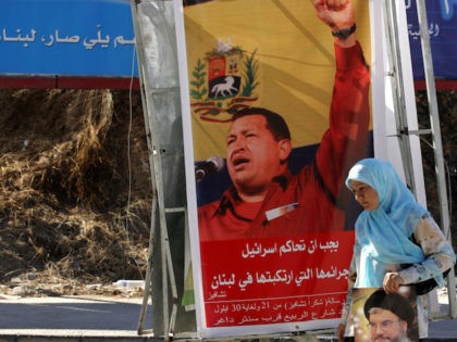 A Lebanese Shiite woman, holding a picture of Hassan Nasrallah, the Secretary General of Hezbollah, walks in front of a poster showing Venezuela's President Hugo Chavez and a slogan that reads: "Gracias Chavez" 21 September 2006 at the southern suburb of Beirut. Chavez stunned the UN General Assembly with a …