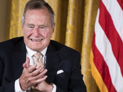 Former US President George H. W. Bush applauds during an event in the East Room of the Whi
