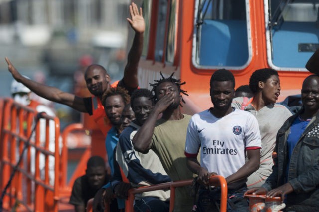 A group of immigrants wave as they arrive on a Spanish coast guard vessel into the souther