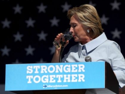Hillary Clinton pauses to take a drink of water to help soothe a cough during a campaign r