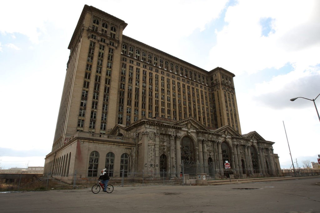 DETROIT - NOVEMBER 20: A man rides his bike past the shuttered Michigan Central Railroad Station November 20, 2008 in Detroit, Michigan. An estimated one in three Detroiters lives in poverty, making the city the poorest large city in America. The Big Three U.S. automakers, General Motors, Ford and Chrysler, are appearing this week in Washington to ask for federal funds to curb to decline of the American auto industry. Detroit, home to the big three, would be hardest hit if the government lets the auto makers fall into bankruptcy. (Photo by Spencer Platt/Getty Images)