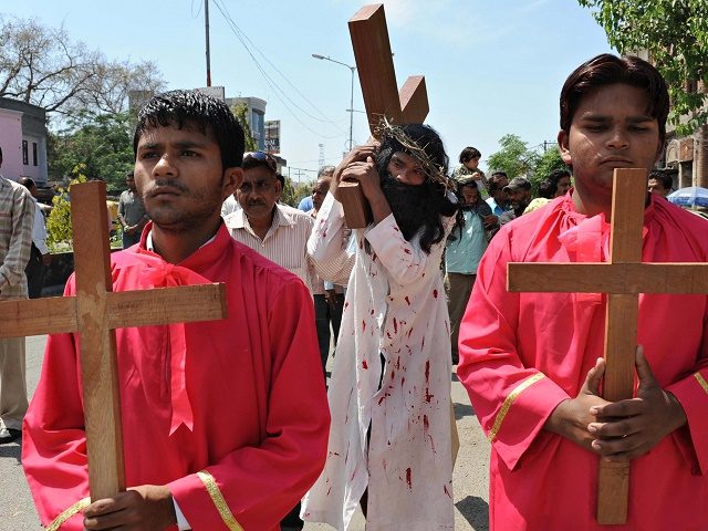 An Indian Christian devotee (C), portraying Jesus Christ, carries a cross as he takes part