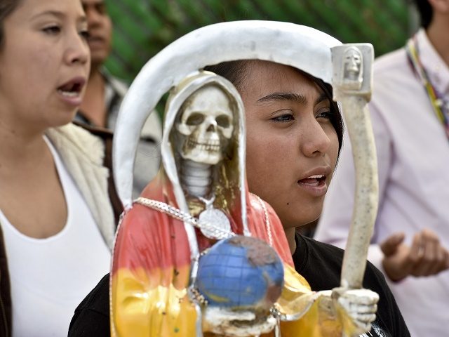 Devotees pray in front of a figure of the Santa Muerte (Holy Death) during a celebration at a sanctuary in Santa Maria Cuautepec, Tultitlan, Mexico on February 7, 2016. Narcos, gangsters and bad guys venerate the Santa Muerte, the Saint of death, probably a syncretism between Middle American and Catholic …