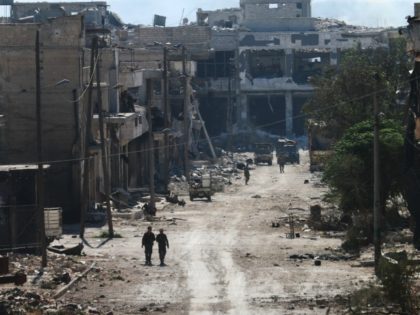 Syrian pro-regime fighters walk in a bombed-out steet in Ramussa on September 9, 2016, aft