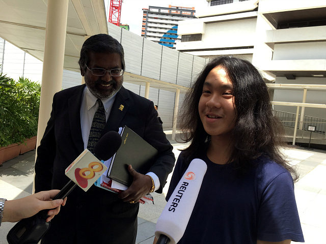 Teen blogger Amos Yee speaks to reporters next to lawyer Nadarajan Kanagavijayan, after he