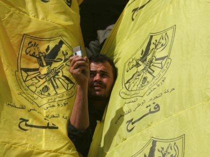 A Palestinian supporter of the secular Fatah movement takes a picture with his mobile phone through his party's flags during a huge gathering in Gaza city, 12 November 2007, to mark the anniversary of the death of Yasser Arafat. Hamas police killed six people in Gaza City today as hundreds …