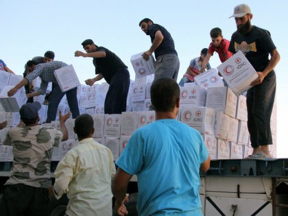 Syrians unload boxes after a 48-truck convoy from the ICRC, SARC and UN entered the Syrian