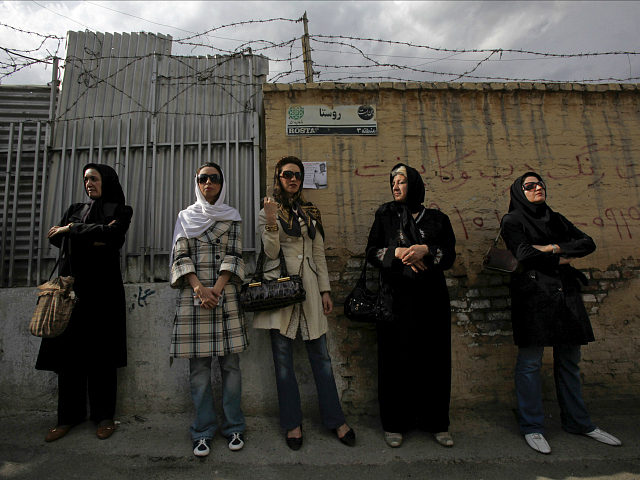 Iranian women wait in line outside a polling station during the Iranian presidential elect