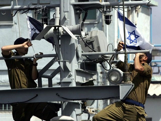 Israeli sailors raise the national and navy flags as they ready to go out on patrol on the