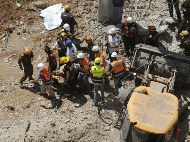 Israeli medics and emergency units carry a wounded person away on a stretcher from a const