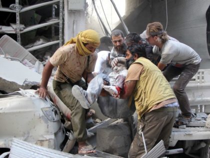 Syrian men evacuate a victim from the rubble of a building following a reported air strike