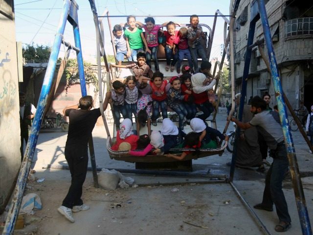 Syrian children ride an attraction in the Syrian rebel-held town of Arbin, in the eastern