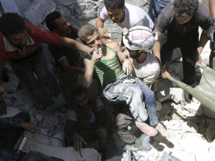 SYRIA, ALEPPO : (FILES) This file photo taken on July 25, 2016 shows Syrian civil defence volunteers, known as the White Helmets, carrying a young boy after they dug him out from under the rubble of buildings destroyed following reported air strikes on the rebel-held neighbourhood of Al-Mashhad in the …