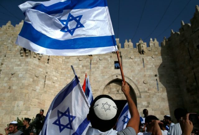 Israelis wave flags outside Damascus Gate in Jerusalem's old city on June 5, 2016 as they